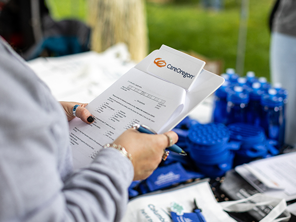 Person's hands holding a clipboard and a pen, with a packet of information on it.