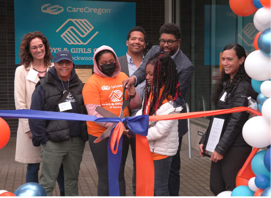 A group of people participating in a ribbon-cutting ceremony outside the CareOregon Boys & Girls Club at Rockwood.