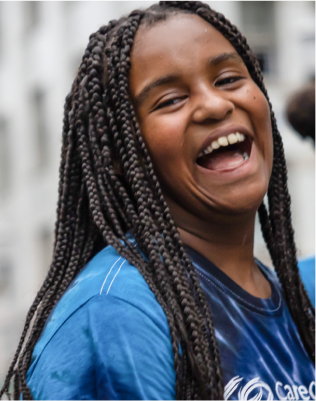 Youth-member-of-the-CareOregon-Boys-Girls-Club-at-Rockwood Person with braided hair wearing a blue shirt, standing in an outdoor setting with a blurred background.
