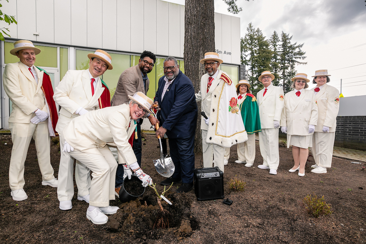 Portland Rosearians pose in front of the CareOregon Rockwood Boys and Girls club while planting a rose bush.