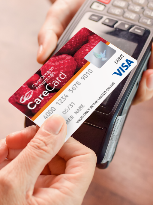 A hand passes the CareOregon Advantage Visa CareCard over a debit card reader. 