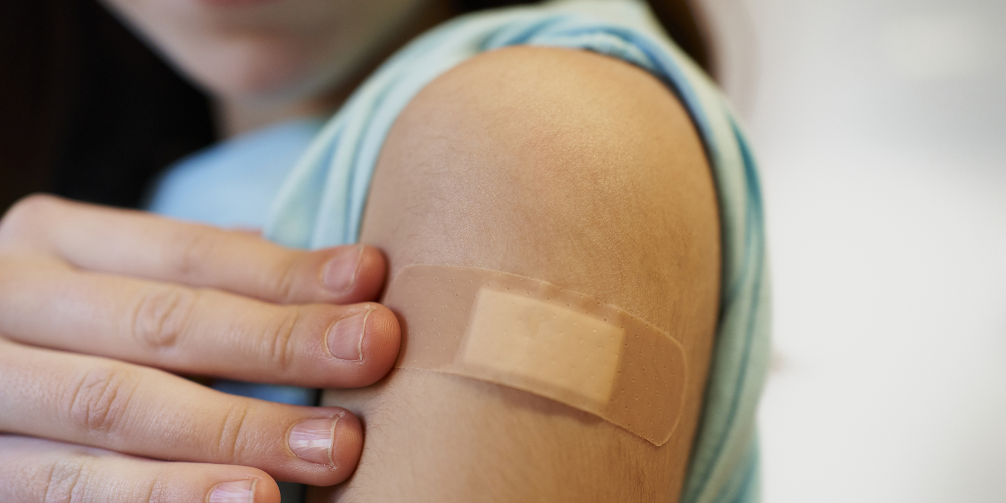 Closeup image of a person with a band aid on their arm.