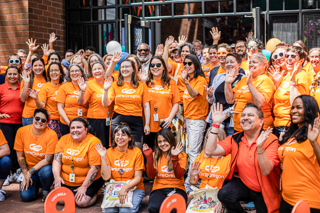 Two people standing side by side with their arms crossed in black and white against a textured orange background.