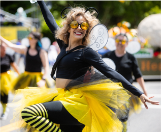 Person in a bee costume with wings, dancing or performing at an outdoor parade 