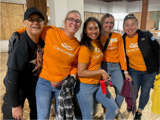 Un grupo de mujeres con camisetas naranjas de CareOregon en una sala en construcción.