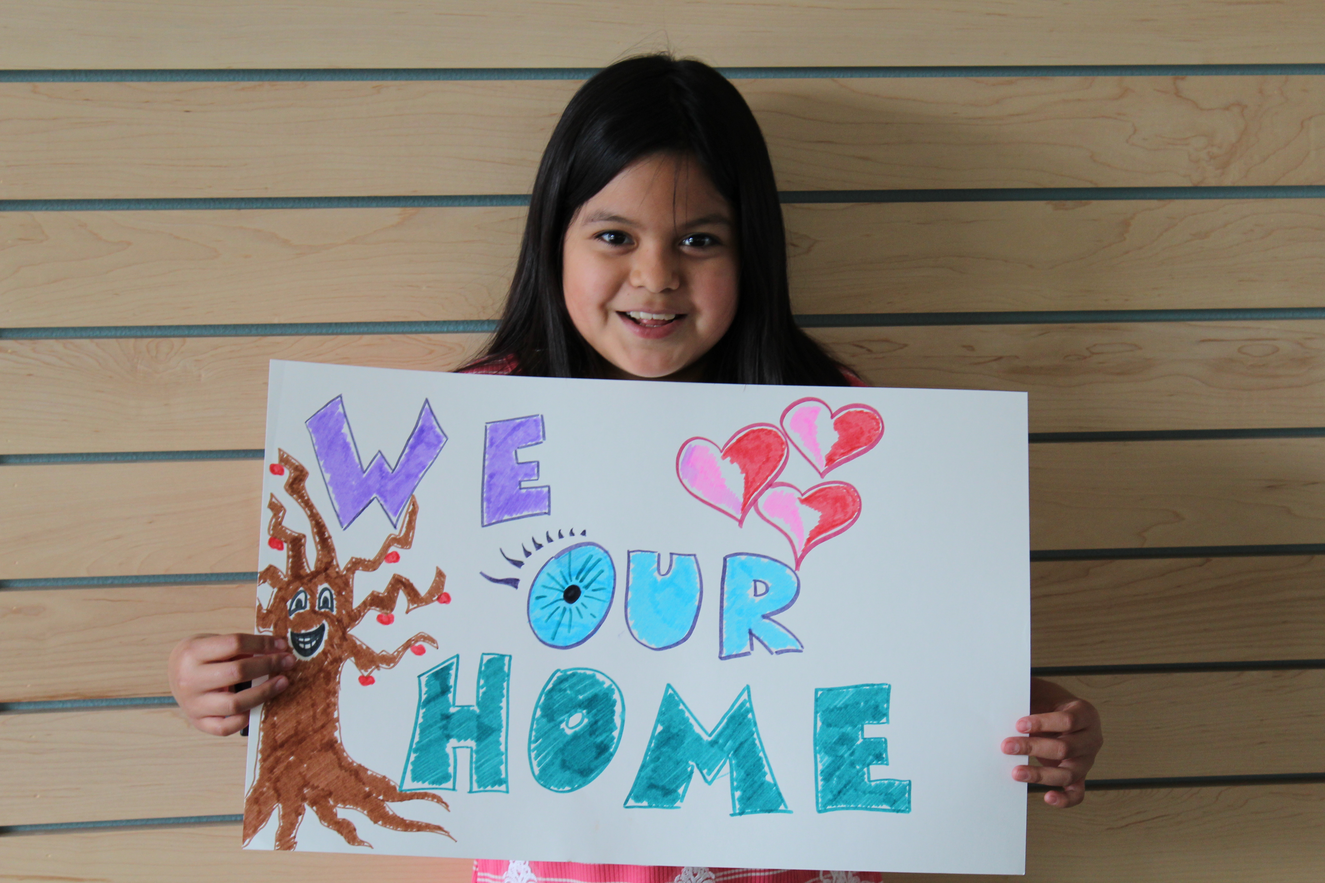Child holding sign that says we love our home