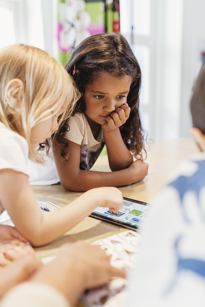 Young children looking at books on a table.