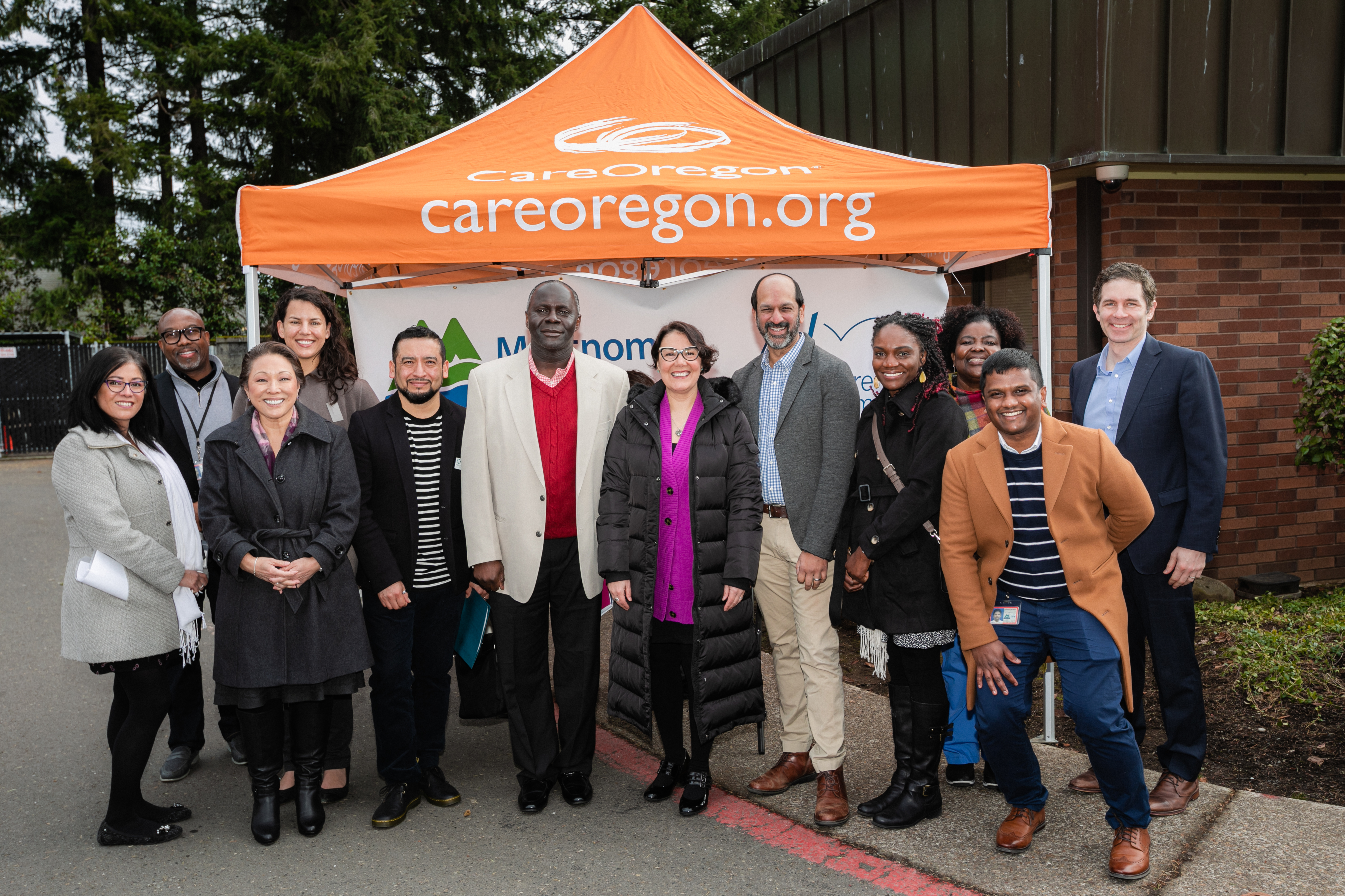A group of people standing in front of a CareOregon tent.