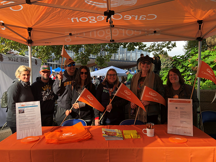 A group of people standing in front of a CareOregon display at the Out of the Darkness Walk